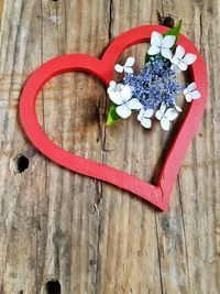 High angle view of flowers and heart shape decoration on wooden table