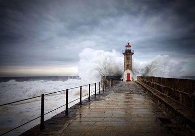 Lighthouse by sea against sky