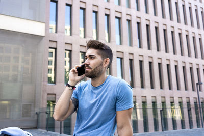 Young man using mobile phone in city