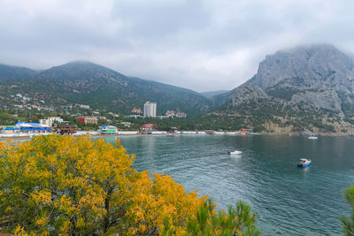 The sea bay with blue water, boats and yachts. in the foreground yellow tree foliage