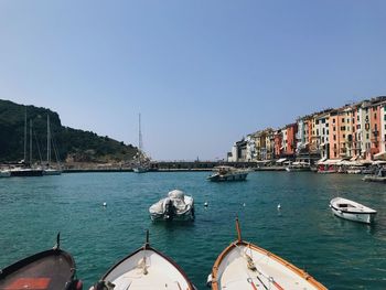 Sailboats moored on sea by buildings against clear sky