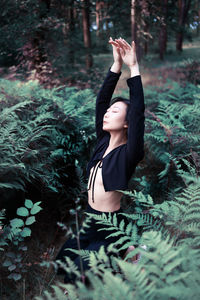 Asian girl posing in forest near fern leaves