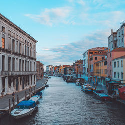 Boats in canal amidst buildings in city