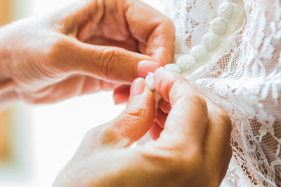 Cropped hands of bridesmaid dressing bride during wedding ceremony