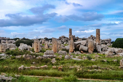 View of old ruins on field against cloudy sky