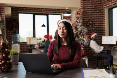 Portrait of woman using laptop while sitting on table