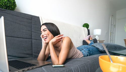 Young woman using mobile phone while sitting on sofa at home