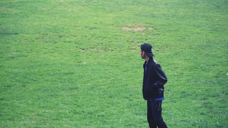 WOMAN STANDING ON GRASSY FIELD