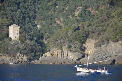 Boats sailing on sea by mountain