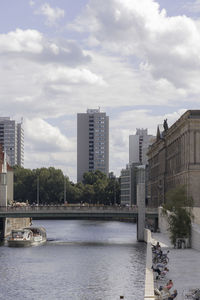 Buildings by river against sky in city