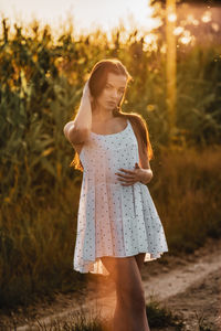 Young beautiful woman in white dress in corn field.