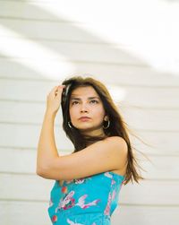 Portrait of a beautiful young woman standing against wall