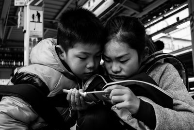Siblings using mobile phone at railroad station platform