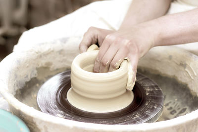 Cropped hands of person molding shape on pottery wheel
