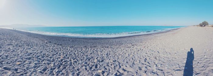 View of calm beach against clear blue sky