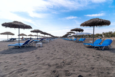 Lounge chairs and parasols on beach against sky