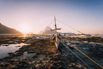 Sailboats moored on sea against sky during sunset