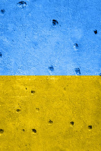 Bullet holes in a wall made during hostilities, in the colors of the ukrainian flag