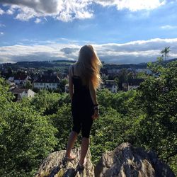 Rear view of woman standing on mountain against sky