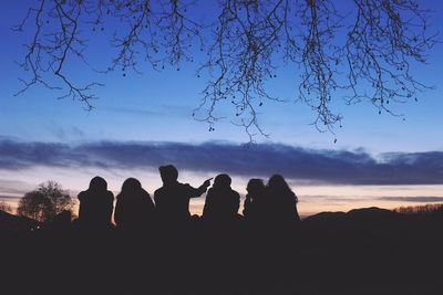 Silhouette friends against sky during sunset