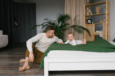Caucasian father playing with cute baby boy on the bed at home. happy family, attractive handsome