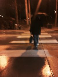 Low section of woman walking on illuminated city at night