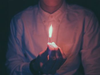 Midsection of man holding burning matchstick