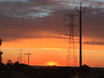 Silhouette of electricity pylon at sunset