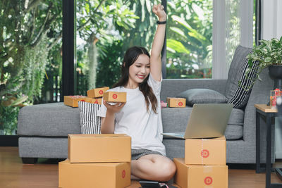 Young woman using phone while sitting in box