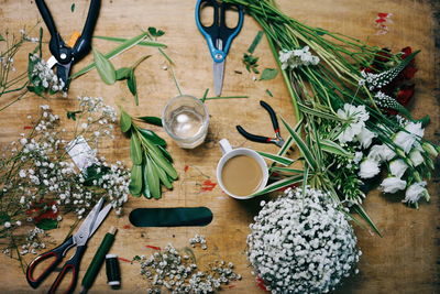High angle view of flowers and scissors on wooden table