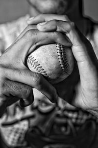 Close-up of man holding baseball ball in hand