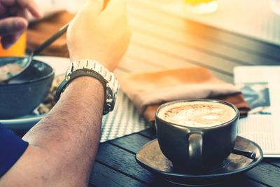 Close-up of hand holding coffee cup on table