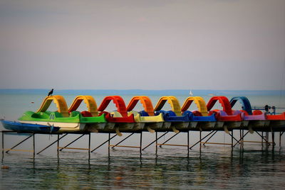 Multi colored chairs by swimming pool against sea against clear sky
