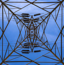 Low angle view of electricity pylon against clear blue sky