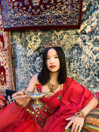 Portrait of young woman standing against building