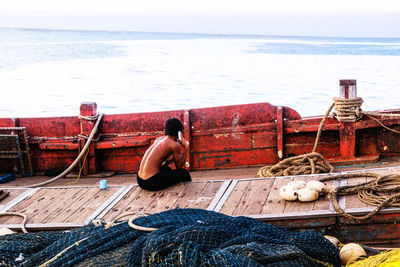 Man fishing on sea shore against sky