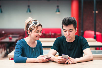 Mother and son using mobile phone at restaurant