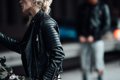 Midsection of woman standing with arms in city