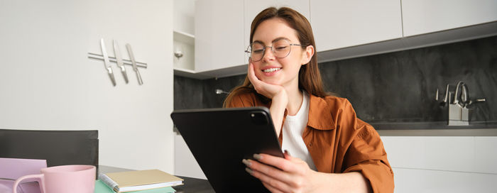 Portrait of young woman using digital tablet while sitting at home