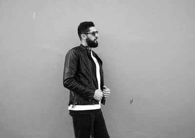 Portrait of young man looking away against wall