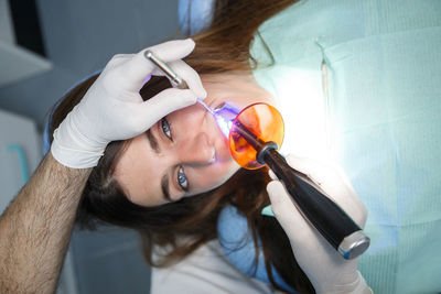 Cropped hands of male dentist treating female patient in clinic