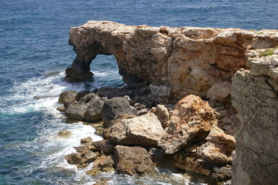 Rock formation at sea shore against sky