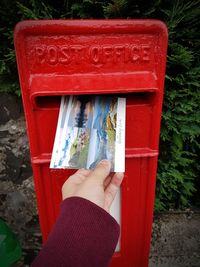 Close-up of hand holding red mailbox