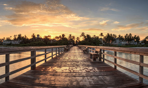 Pier amidst trees against sky during sunset