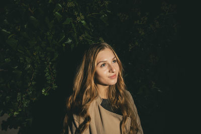 Beautiful young woman standing against plants