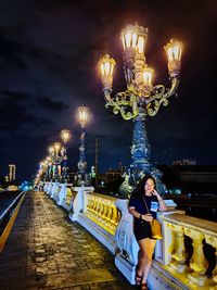 Full length of woman standing in illuminated city at night