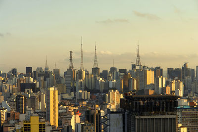 Modern buildings in city against sky during sunset