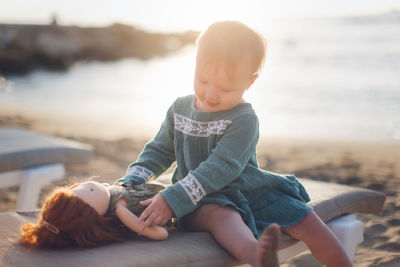 Cute baby playing with doll at beach