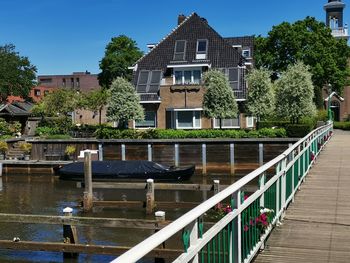 Footbridge over canal by buildings against sky