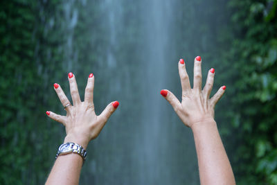 Close-up of woman hands against waterfall